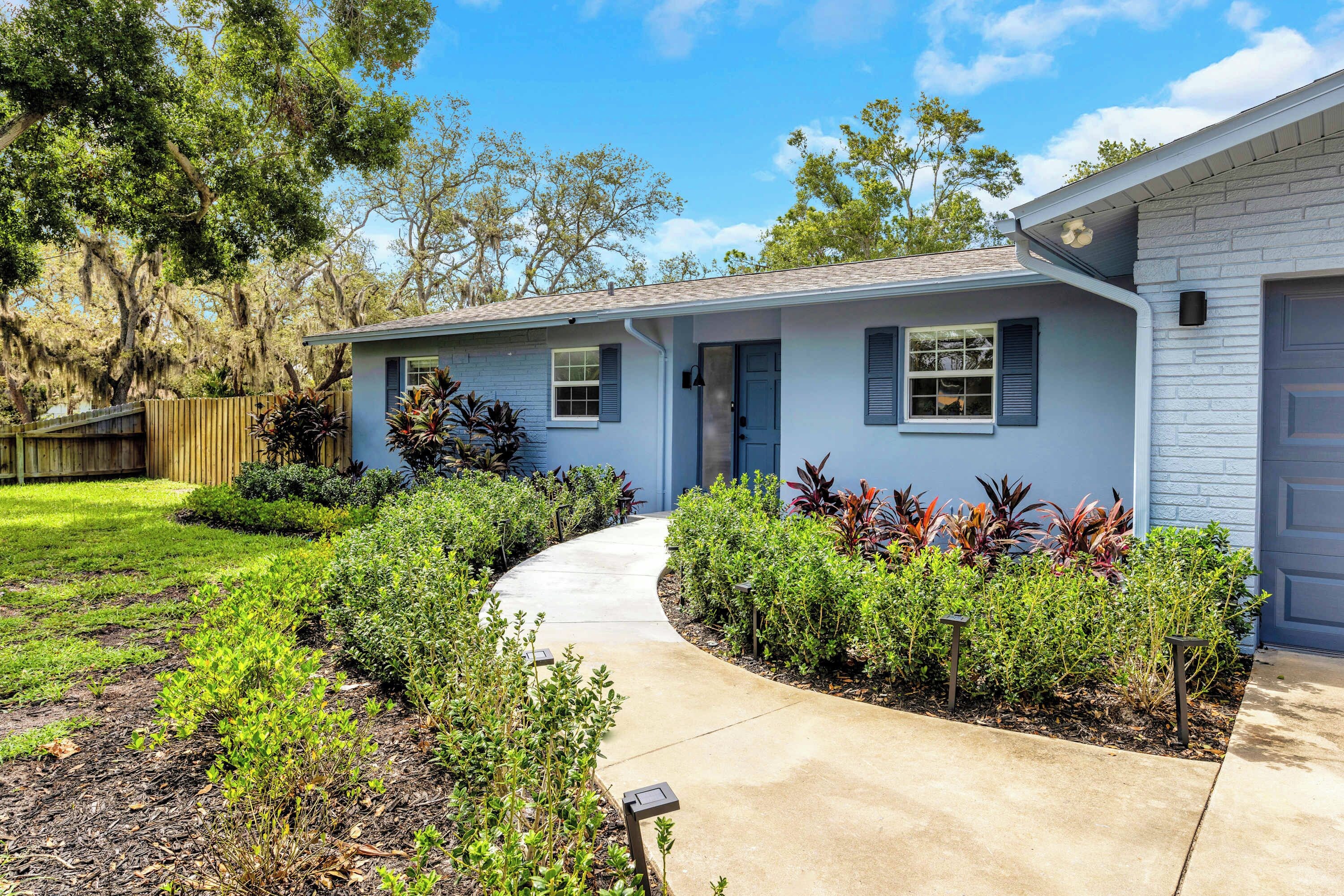 A residential house with a front yard, a pathway leading to the entrance, and a variety of shrubs and plants.