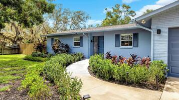 A residential house with a front yard, a pathway leading to the entrance, and a variety of shrubs and plants.