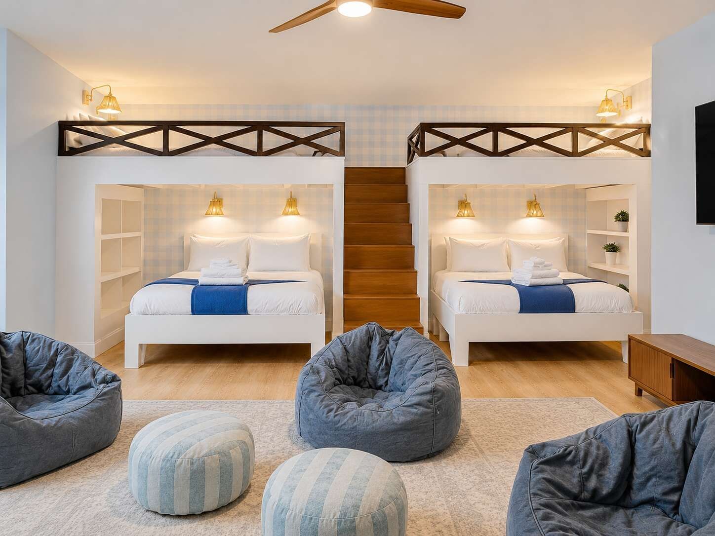 A bedroom with two beds, a ceiling fan, and a staircase.