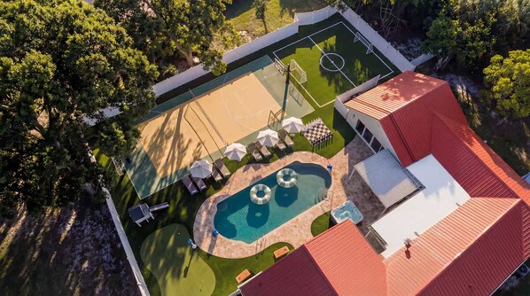 An aerial view of a property with a tennis court, a swimming pool, and a covered patio area. - Heated Pool—Gym—Hot tub—Pickleball—Near Beach (Largo)