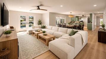 A spacious living area with a large sofa, two coffee tables, and a television.