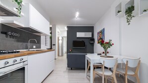 Een moderne keuken met witte kastjes, een houten aanrechtblad en een ingebouwde kookplaat.