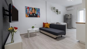 Een moderne woonkamer met een grijze bank, een klein wit tafeltje en een schilderij aan de muur.