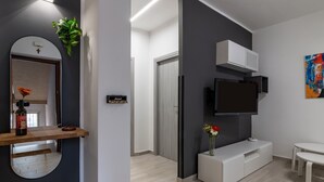 Een moderne woonkamer met een flatscreen televisie, een witte entertainmentkast en een klein, wit tafeltje.