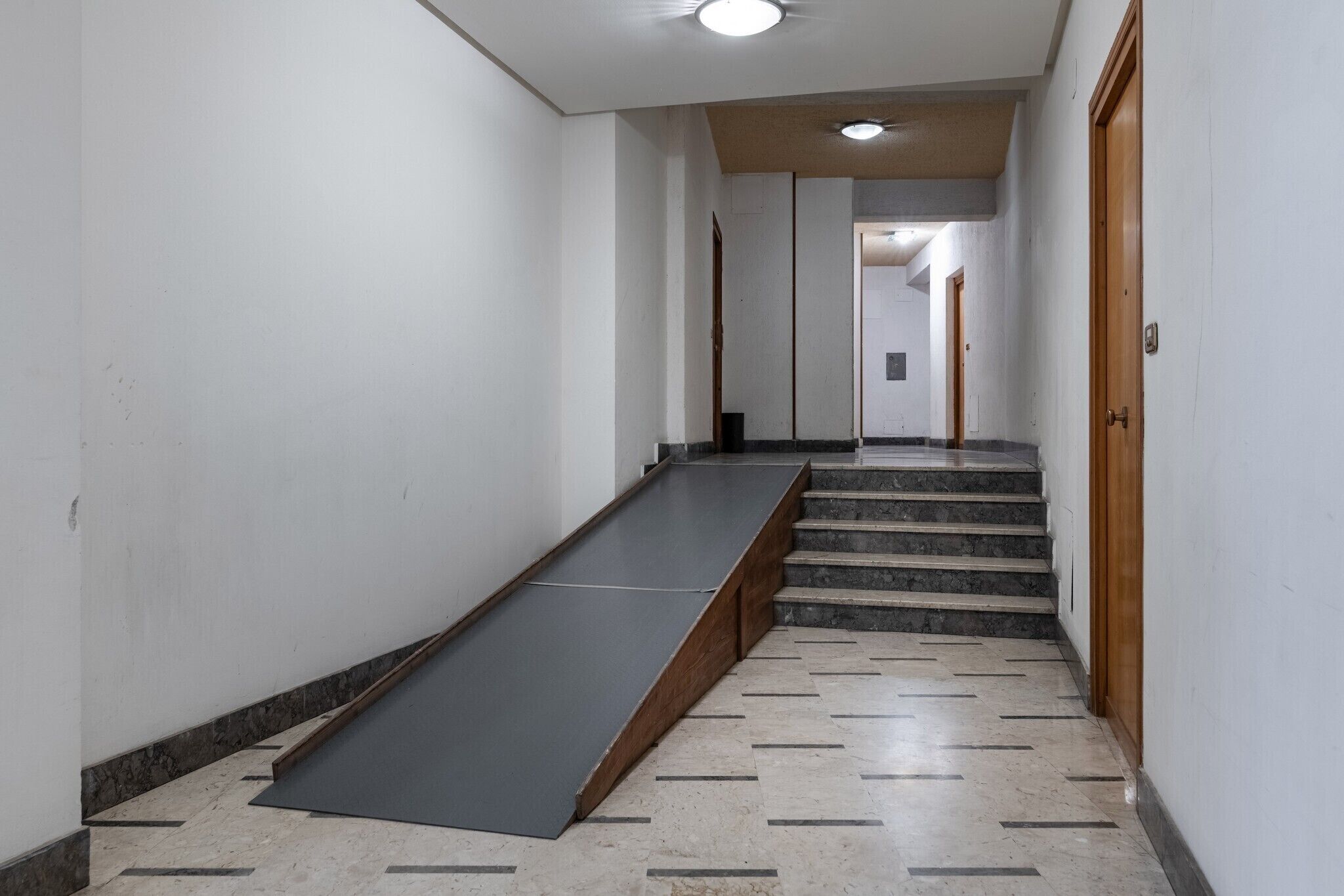 Un couloir avec une rampe menant à un escalier.
