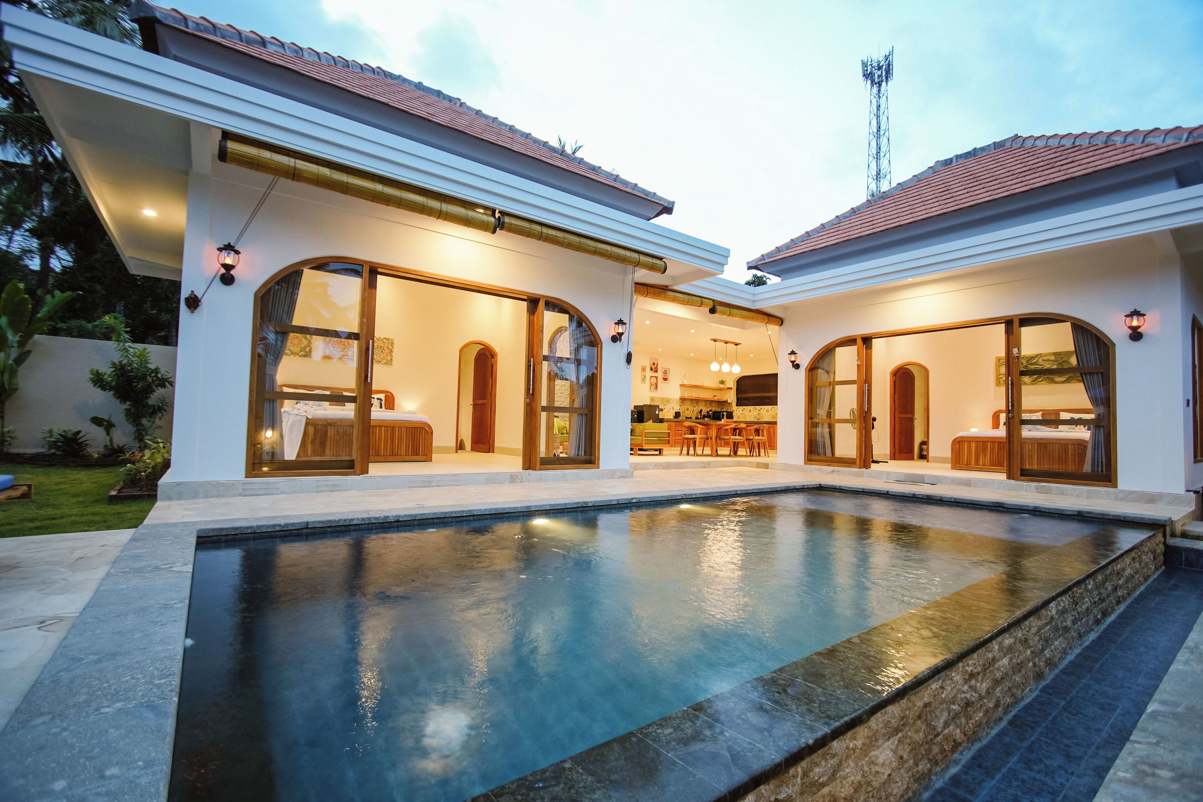 Une maison moderne dotée d’une piscine, de grandes portes vitrées et d’un intérieur bien éclairé.