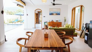 Un comedor moderno con una mesa y sillas de madera, un ventilador de techo y vistas al exterior.