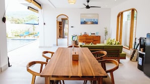 Un comedor moderno con una mesa y sillas de madera, un ventilador de techo y vistas al exterior.
