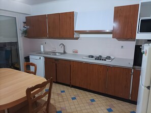 A kitchen with wooden cabinets, a sink, a stove, and a refrigerator. - Apartment 'Détente' with Balcony and Wi-Fi (Chamole)