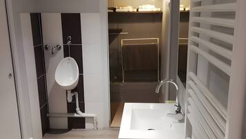 A modern bathroom with a white sink, a mirror, and a shower area.