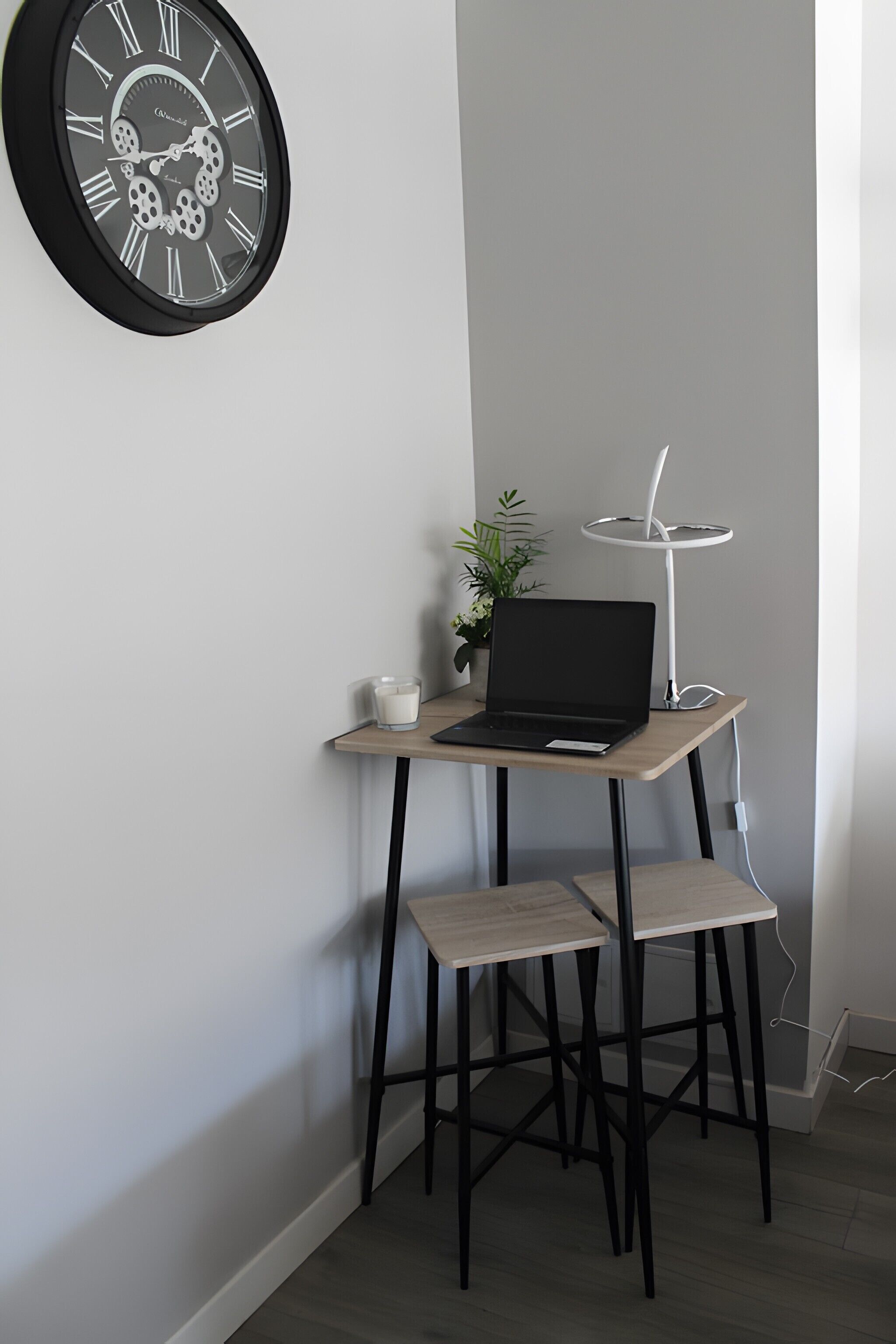Een hoekbureau met een laptop, een witte kaars en een potplant.