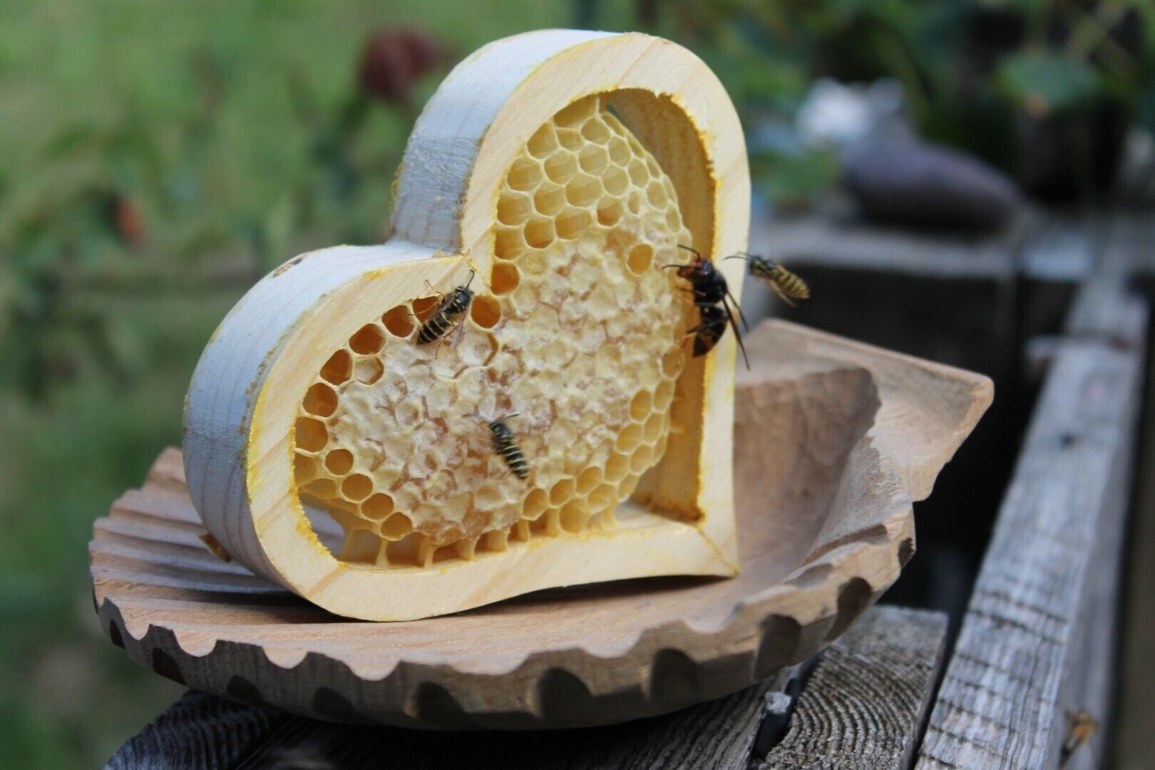 Ein herzförmiges Holzobjekt mit Bienen auf einer Holzeinlage.