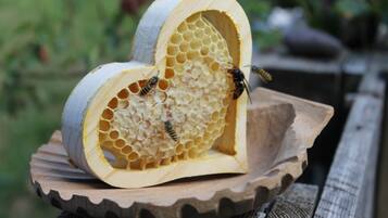 Ein herzförmiges Holzobjekt mit Bienen auf einer Holzeinlage.