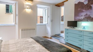 Ein Schlafzimmer mit einem Bett, einem Schminktisch, einem Fernseher und einem Bild an der Wand.
