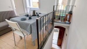 Ein Essbereich mit Tisch für vier Personen, einer Couch und einer Treppe, die zu einer oberen Ebene führt.
