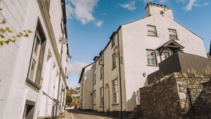 A narrow street with white buildings, a stone wall, and a clear blue sky. - Old Village Shop, Ambleside, central, cosy retreat (Ambleside)