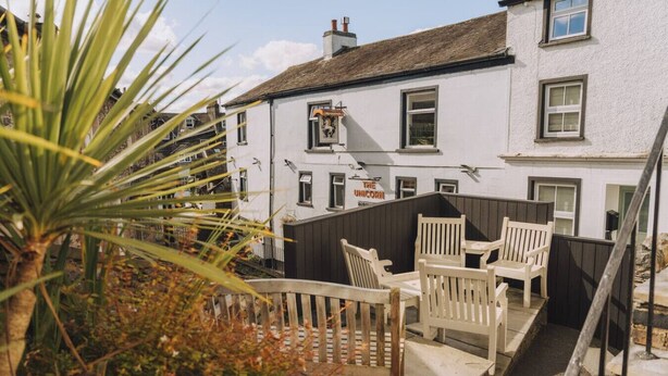 A white building with a sign reading "The Unicorn" and a balcony with wooden chairs. - Old Village Shop, Ambleside, central, cosy retreat (Ambleside)