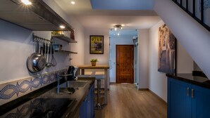 A modern kitchen with a wooden floor, a built-in stove, and a hanging pot rack. - Lovely cottage for 2 people, roof terrace, 10 minutes from the beach! (Ojén)