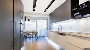 A modern kitchen with grey cabinets, a white countertop, and a dining area with a table and chairs.
