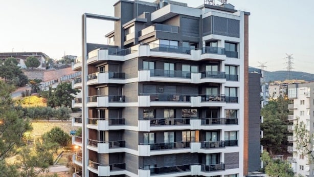 A modern multi-story hotel with balconies, a swimming pool, and a view of the surrounding area.