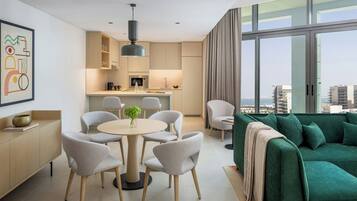 A modern living space with a dining area, kitchen, and a green sofa with a view.
