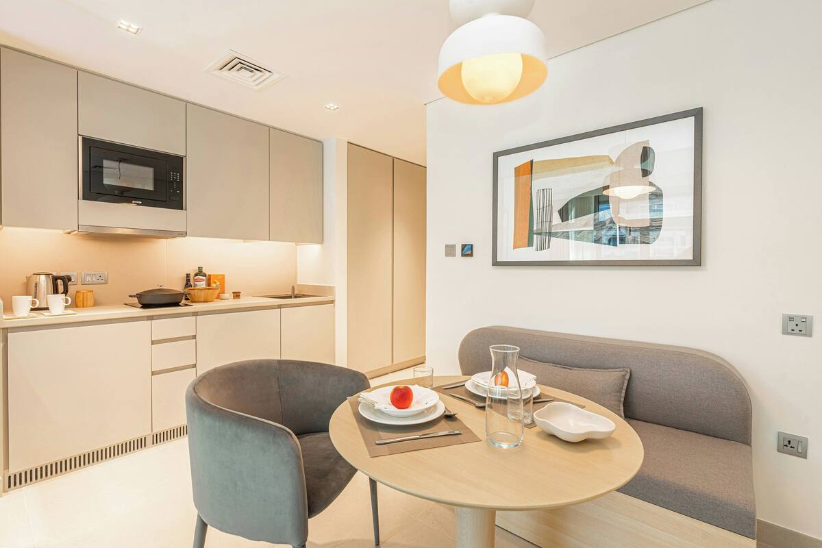 A modern kitchen with a microwave, cabinets, and a dining area with a table, chairs, and a sofa.