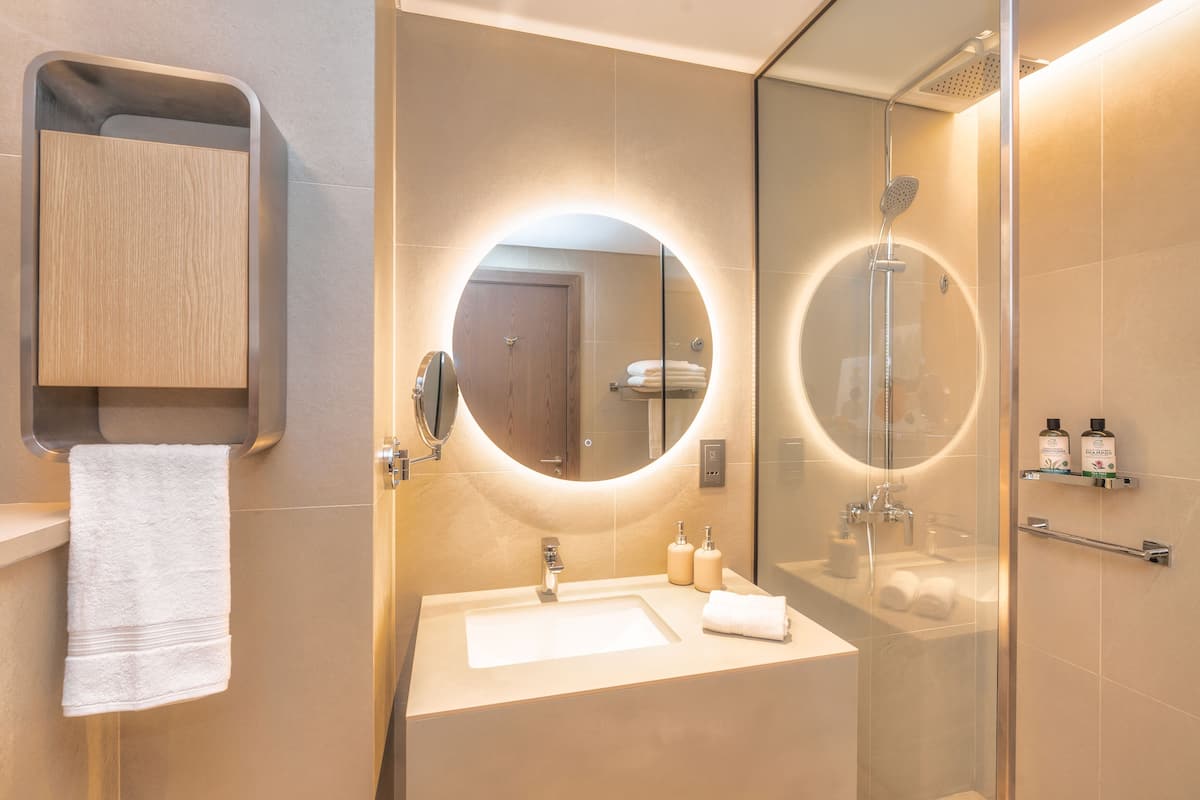 A modern bathroom with a large mirror, a sink, and a glass-enclosed shower.