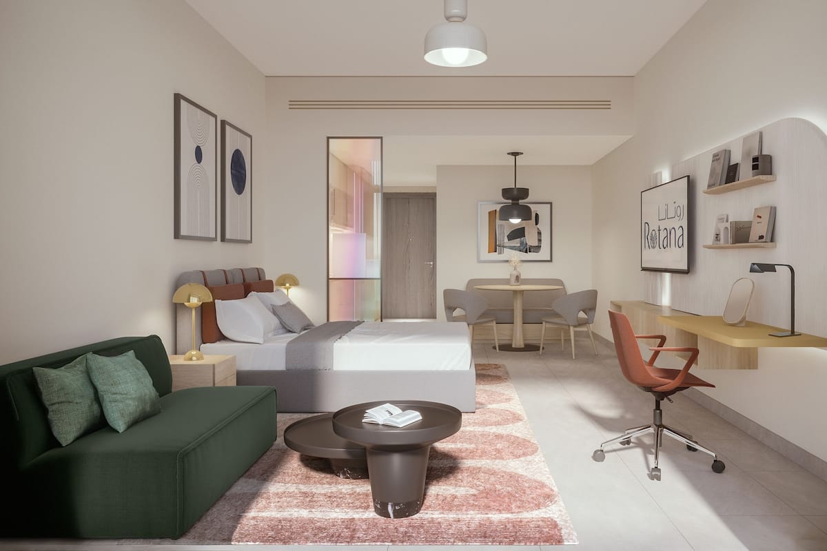 Una habitación de hotel moderna con una cama, un sofá verde, un escritorio y una zona de comedor.