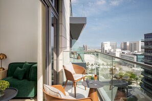 Ein Balkon mit einer Couch, Stühlen und einem Tisch, mit Blick auf eine Stadtlandschaft und einen Strand.