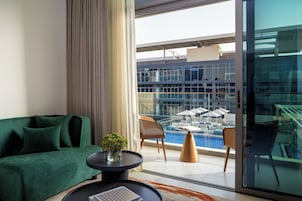 Un moderno salón con un sofá verde, una mesa de centro y vistas a una zona de piscina en la azotea.