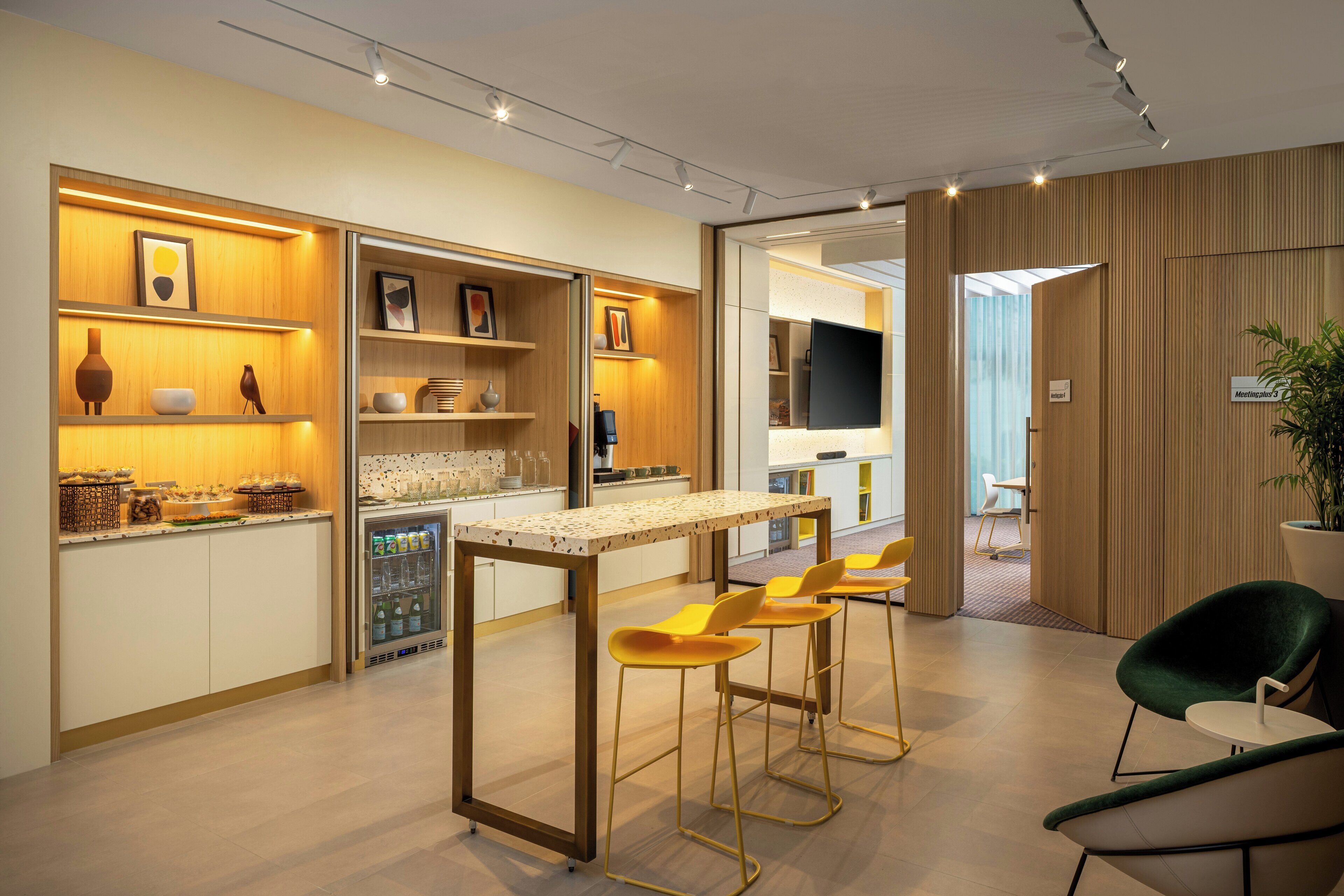 Una cocina moderna con barra, refrigerador y zona de estar con sillas.