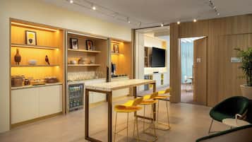 Una cocina moderna con barra, refrigerador y zona de estar con sillas.