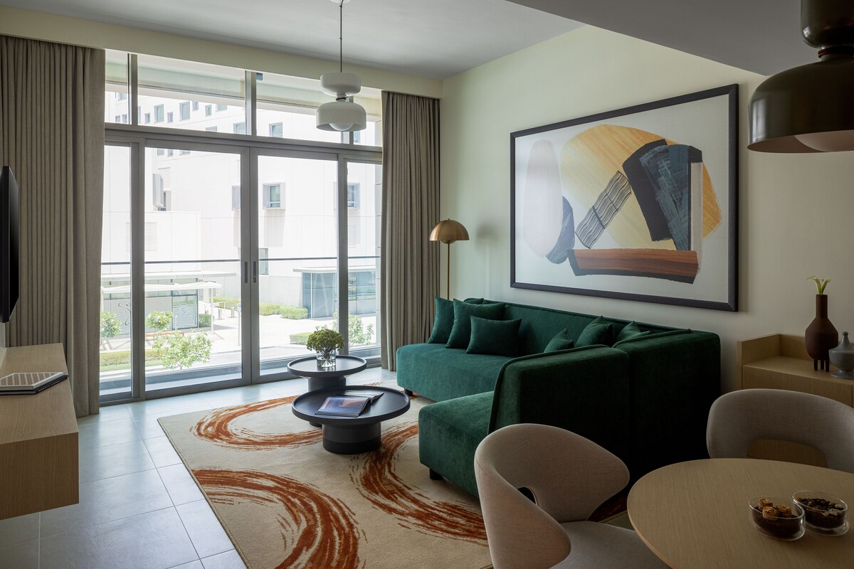 Una sala de estar moderna con un sofá verde, una mesa de centro y un ventanal grande.