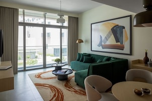 Una sala de estar moderna con un sofá verde, una mesa de centro y un ventanal grande.