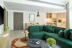 Una sala moderna con un sofá verde, una mesa de centro y un televisor.