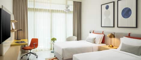 A hotel room with two beds, a desk with a chair, a television, and artwork on the wall.