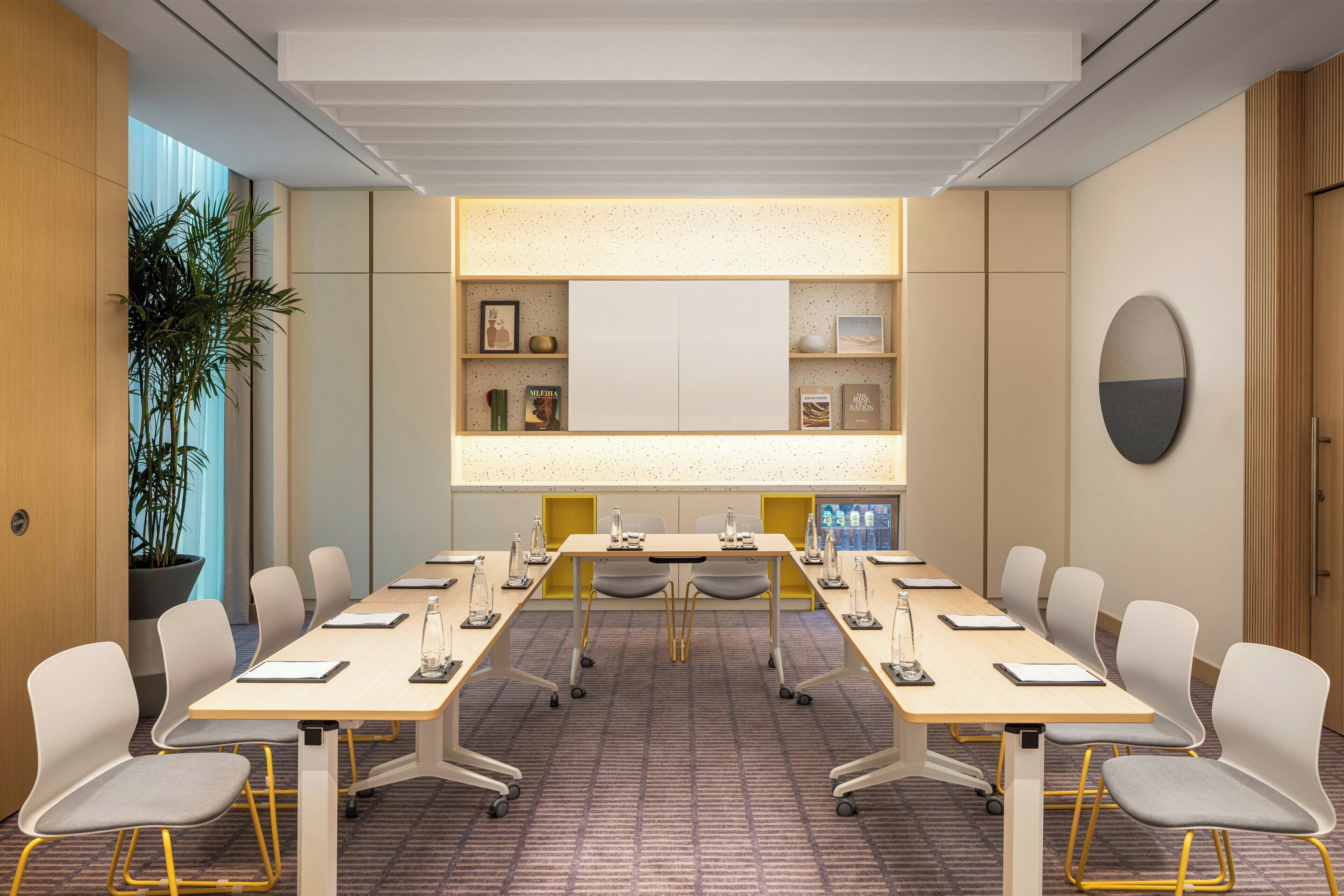 A conference room with a long table, chairs, a whiteboard, and shelves with books and decorative items.