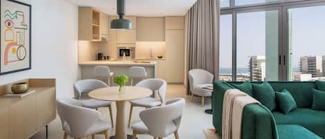 A modern apartment with a dining area, kitchen, and a green sofa with a view of the city.