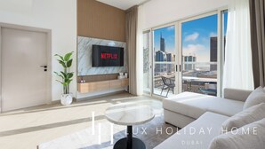 Een moderne woonkamer met een flatscreen televisie, een bank, een salontafel en een groot raam met uitzicht op de stad.