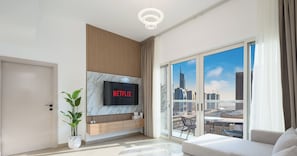 A modern living room with a flat-screen TV, a sofa, a coffee table, and a large window with a city view. - LUX The Marina View Suite 3 (Dubai)