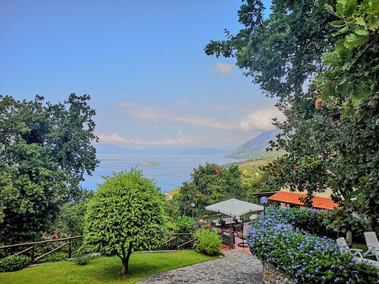 A pathway leading to a seating area with a view of the sea and mountains.