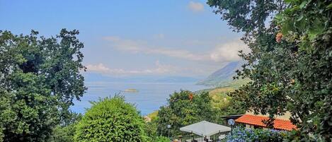 A pathway leading to a seating area with a view of the sea and mountains.