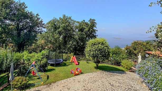 Un jardín con un sendero de piedra, un trampolín y un tobogán.