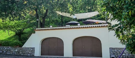 A building with two arched doors, a stone wall, and a paved area.