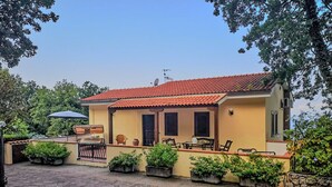 Una casa con techo de tejas, patio empedrado y plantas en macetas a lo largo de las paredes.