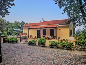 Ein Haus mit Ziegeldach, einem gepflasterten Innenhof und Kübelpflanzen an den Wänden.