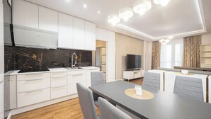 Eine moderne Küche mit weißen Schränken, einer schwarzen Marmorfliesenspiegel und einem Essbereich mit Tisch und Stühlen.