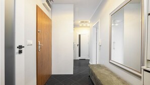 Ein Korridor mit einer Holztür, einer Sitzbank und einem großen Spiegel an der rechten Wand.