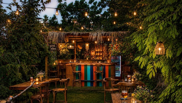 An outdoor bar area with wooden furniture, a fire pit, and string lights. - Granma Butik Apart Otel (Bodrum)