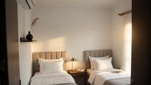 A hotel room with two beds, a bedside table with a lamp, a vase with dried plants, and a window with curtains. - Granma Butik Apart Otel (Bodrum)